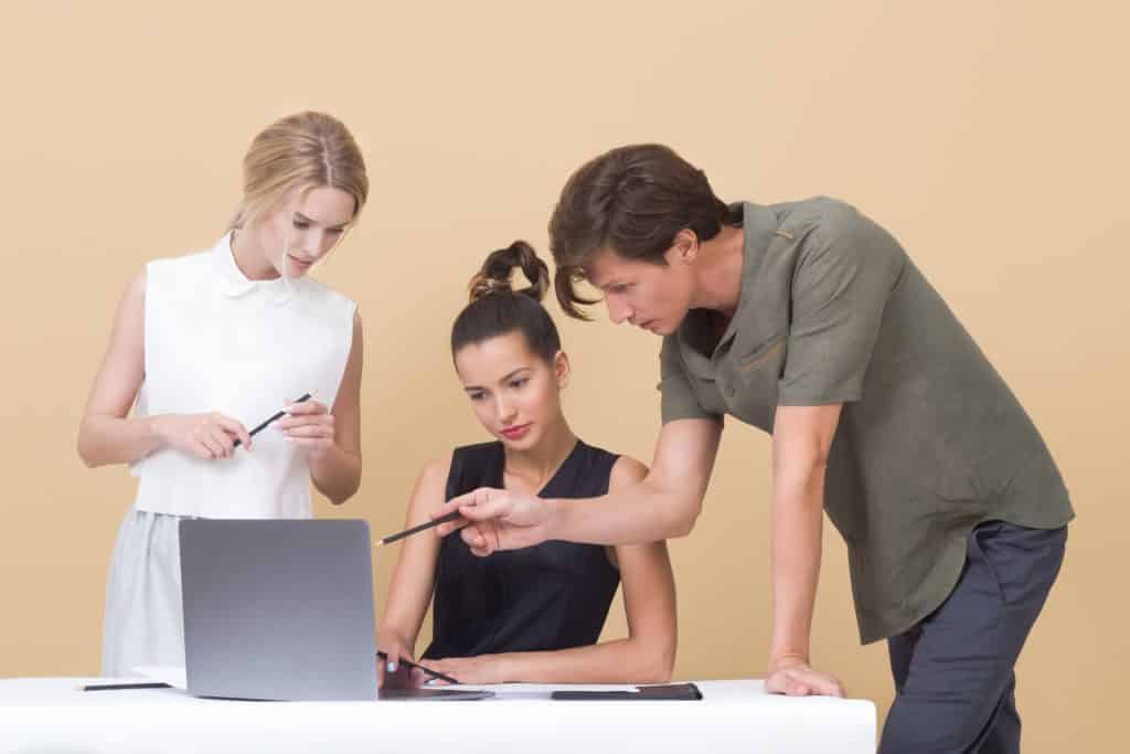 two woman and one man looking at the laptop 1036641